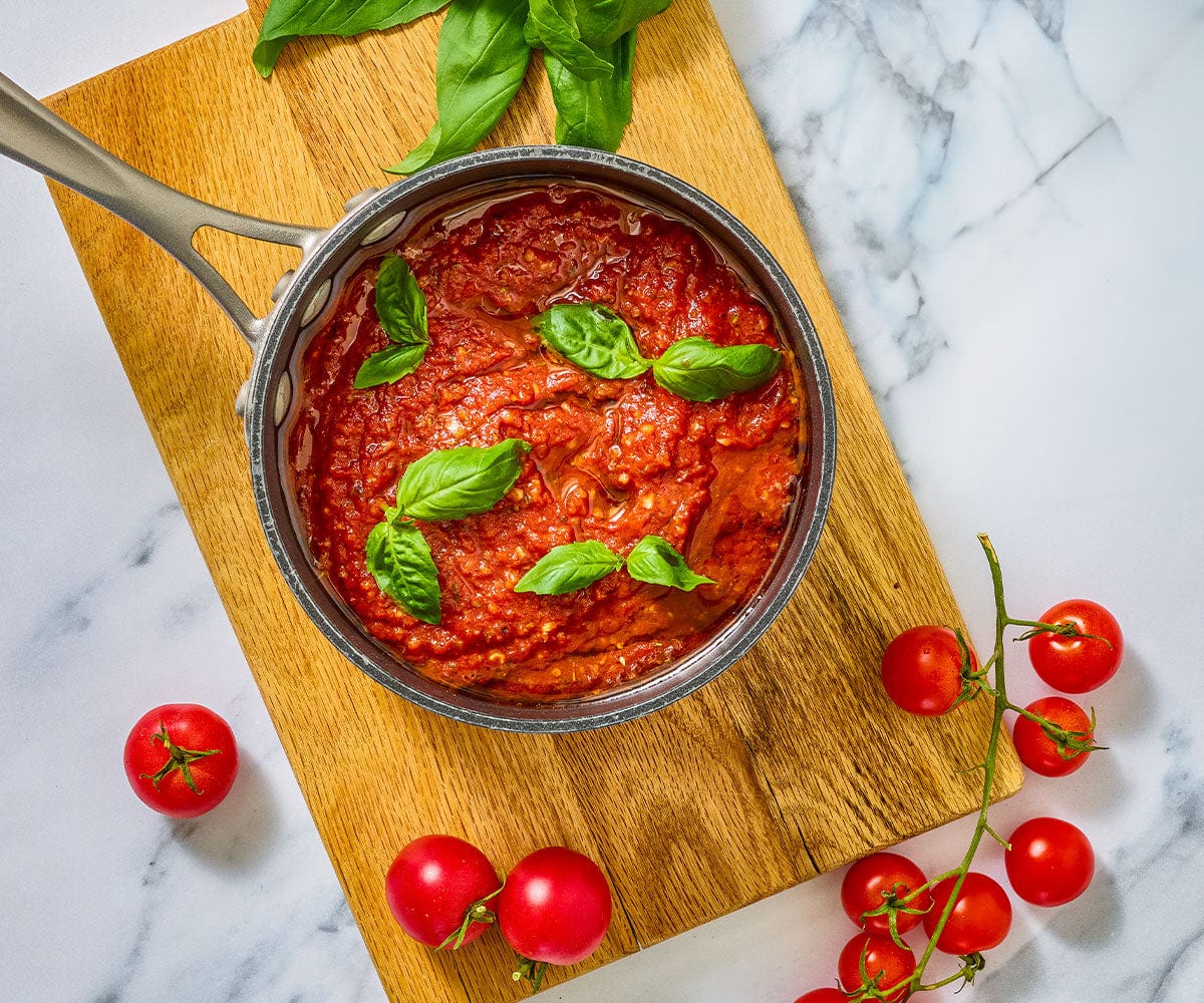 Overhead image of a pot of made classic marinara sauce with basil.