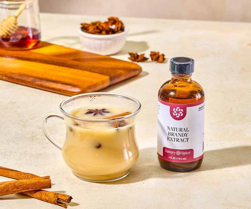 Bottle of natural brandy extract next to a glass mug of chai.