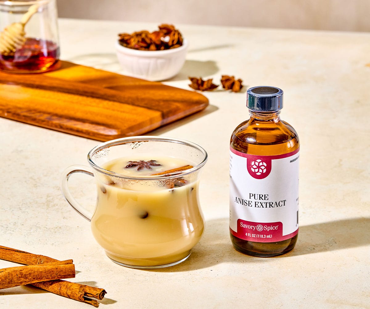 Bottle of pure anise extract next to a glass mug of chai.