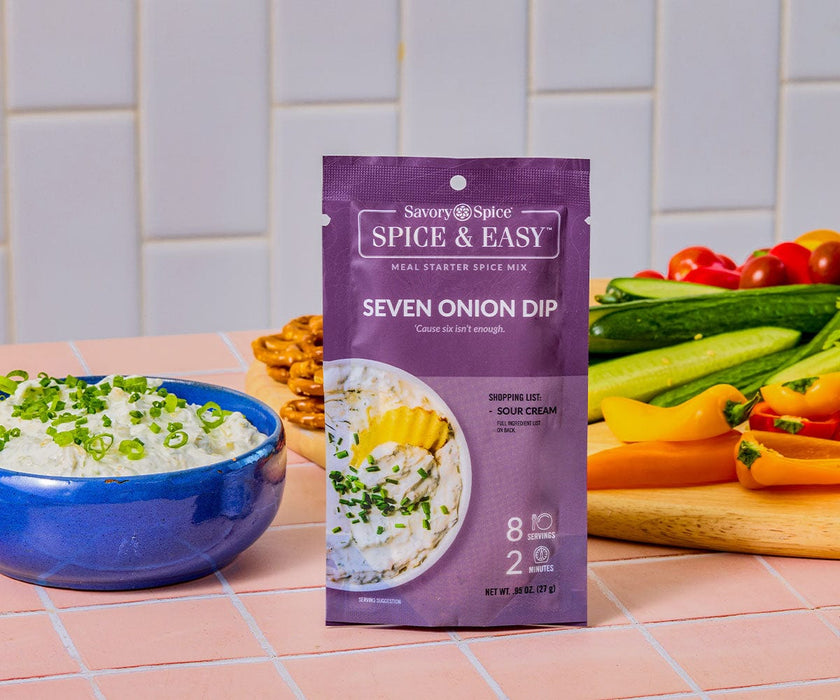 Image of a package of seven onion dip Spice & Easy next to a finished bowl of the dip and a plate of fresh vegetables. 