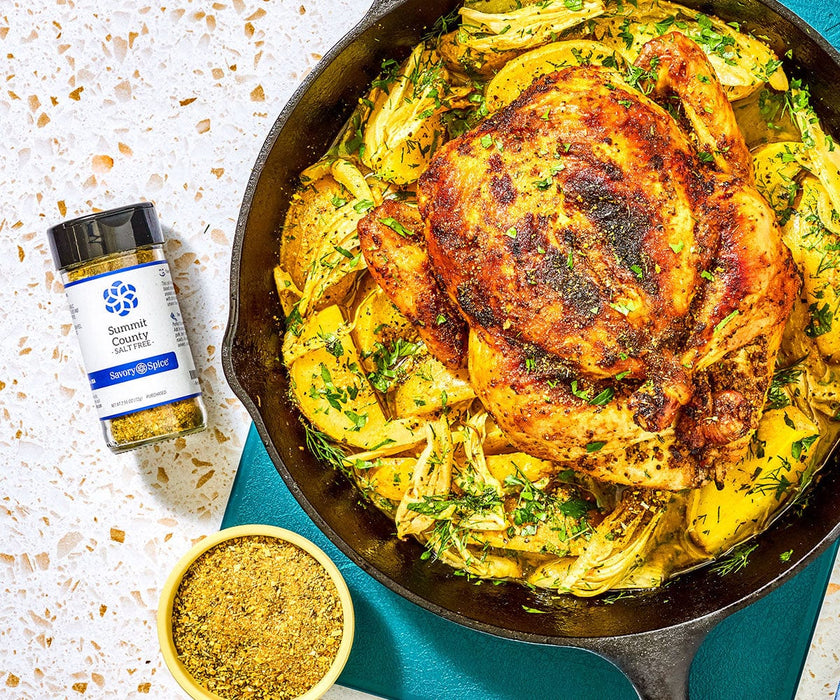 Image of a jar of Summit Country salt free seasoning next to a whole roast skillet chicken with fennel and potatoes. 